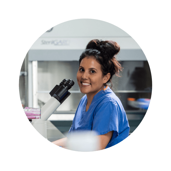 Smiling female Charles River laboratory professional in front of a microscope