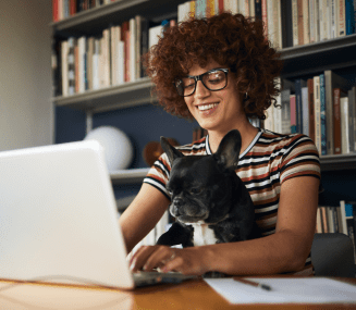 Young female student at a laptop with a dog in her lap