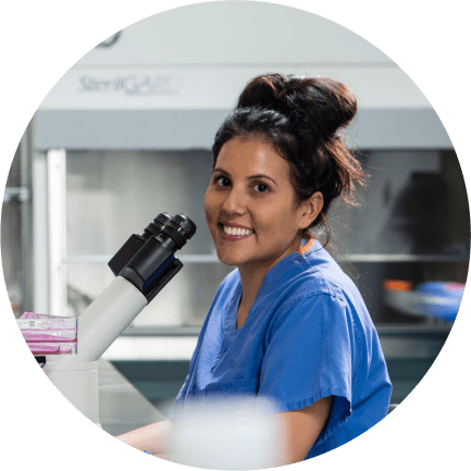 Smiling female Charles River laboratory professional in front of a microscope