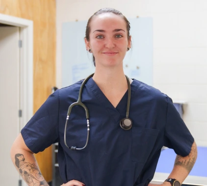 Una donna sicura di sé, veterinaria di Charles River Laboratories, specializzata in primati non umani (NHP), con le mani sui fianchi.