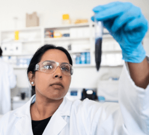 Scientist examining a test tube in a laboratory setting, wearing safety goggles.